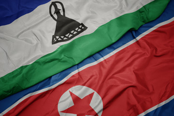 waving colorful flag of north korea and national flag of lesotho.