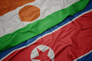 waving colorful flag of north korea and national flag of niger.