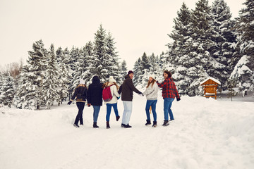 Friends run through the snow in the park in winter