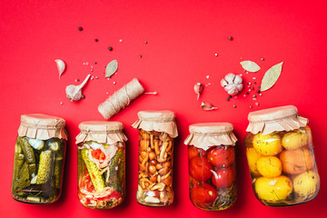 Сucumber, squash and tomatoes pickling and canning into glass jars. Ingredients for vegetables preserving. Healthy fermented food concept. Top view. Copy space.