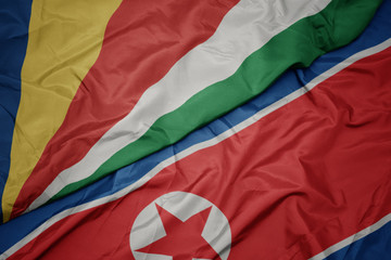 waving colorful flag of north korea and national flag of seychelles.