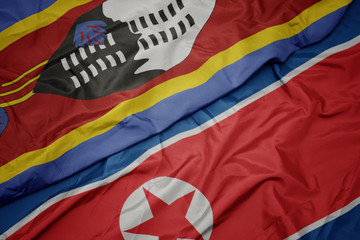 waving colorful flag of north korea and national flag of swaziland.