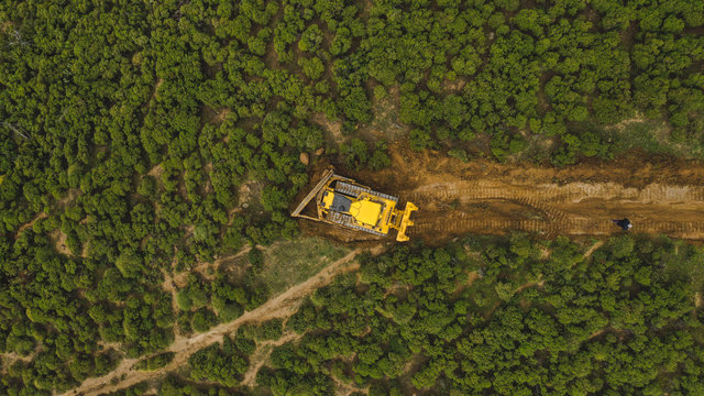 Aerial view of yellow machine doferstating beautiful trees in mountains of Marbella, Spain