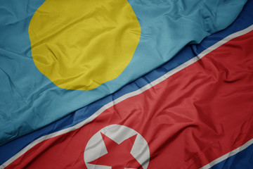waving colorful flag of north korea and national flag of Palau .