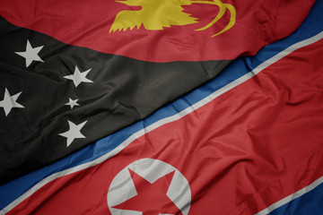 waving colorful flag of north korea and national flag of Papua New Guinea .
