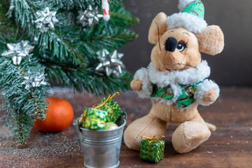 Christmas rat near a snowy branch. New Year. Festive mood, New Year's toys and gifts. Copy space. 