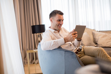 Handsome young man using digital tablet at luxury apartment