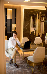 Young man sitting in a luxurious room in front of a laptop computer