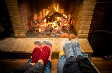 Mother father and kids sitting at cosy fireplace on Christmas time - Lovely family resting together on woolen socks at home fire place - Winter holiday and x mas concept on comfy warm flame filter