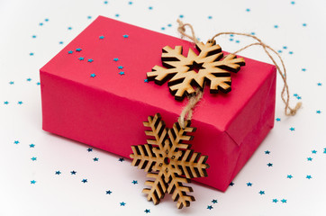 Pink gift box on a white background adorned with shiny blue stars and wooden snowflakes. Preparing...