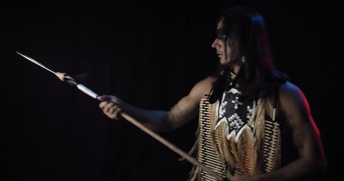 Native american man with a spear is poking, black background, 4k