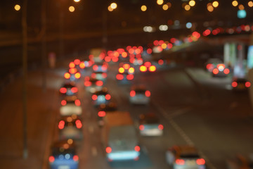 Fototapeta na wymiar Defocused photography of urban night traffic. The lights of blurred motion at the highway. The road is filled out cars.