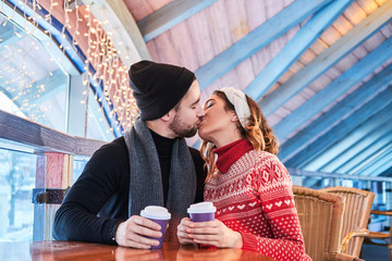 Young couple on a date in cafe, talking and kissing at Christmas time