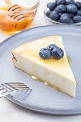 Piece of cheese casserole or cheesecake, garnished with blueberry and honey, on  gray plate, vertical, closeup