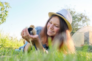 Portrait of beautiful girl on farm with two newborn chicks in hand
