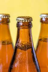 A chilled bottles with drink on yellow background. Beer in a dewy glass bottle closed with a lid.