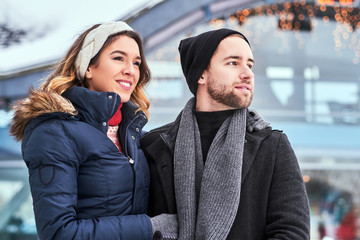 Happy couple dating in the ice rink, hugging and enjoying winter time