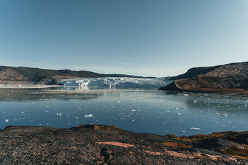 Obraz premium Panoramic image of Camp Eqi at Eqip Sermia Glacier in Greenland. nature landscape with lodge cabins. Midnight sun and pink sky. Tourist destination Eqi glacier in West Greenland AKA Ilulissat and
