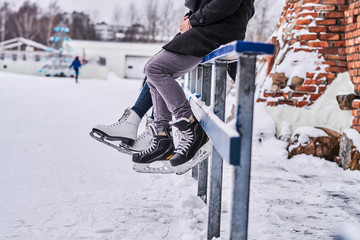 Couple wearing ice skates sitting on a guardrail