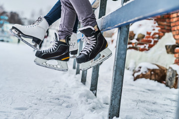 Couple wearing ice skates sitting on a guardrail