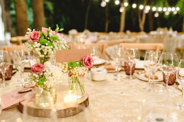 Flowers decorating the centerpieces with luxury cutlery on the tables of a wedding hall.