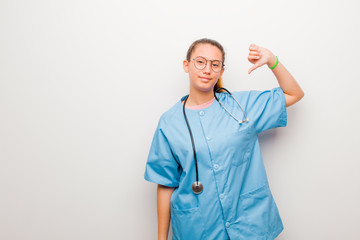 young latin nurse feeling proud, arrogant and confident, looking satisfied and successful, pointing...