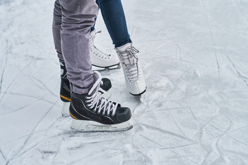 Young loving couple skating at ice rink outdoors, close-up view of the skates