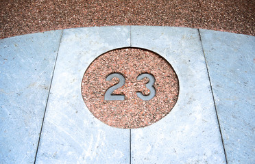 Number 23, twenty-three, in a circle, on a stone wall.