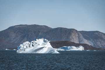 Huge floating iceberg in deep blue ocean water. Greenland and Antarctica, near Ilulissat. Global warming concept. Blue Sky and ice fjord.