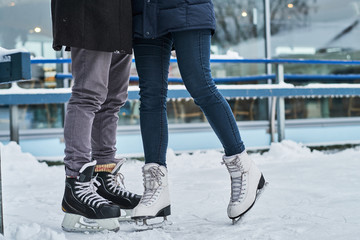 Happy young couple dating in the ice rink, hugging and enjoying winter time