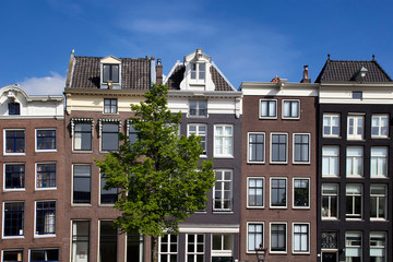 Close up view of historical, traditional and typical buildings showing Dutch architectural style in Amsterdam. It is a sunny summer day with clear blue sky.