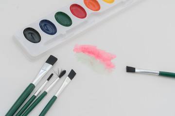 Artistic creations are made with brushes, paints and paper which forms a work of art.