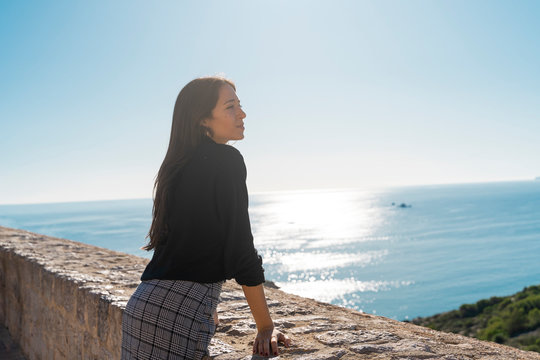 Young brunette woman looking at distance vom viewpoint in Ibiza