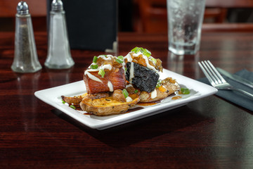 Pork belly served over potatoes. An upscale menu item in a fancy pub. Charred pork belly with cream sauce. 