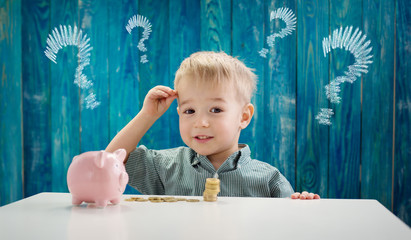 three years old child sitting st the table with money coins and biggybank