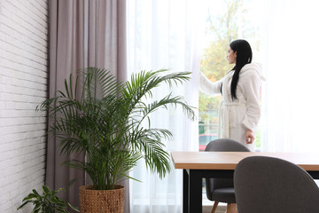 Woman near window in room decorated with plants. Home design ideas