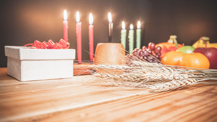 Kwanzaa holiday concept with decorate seven candles red, black and green, gift box, pumpkin,corn and fruit on wooden desk and background.