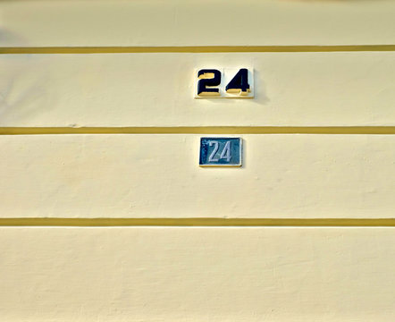 Numbers 24, twenty four, on pale yellow wall.