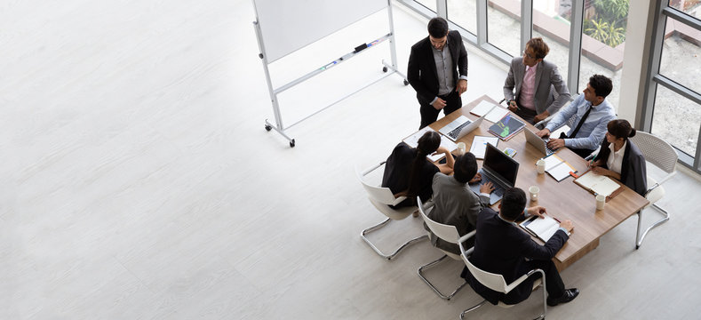 Top view of group of multiethnic busy people working in an office, Aerial view with businessman and businesswoman sitting around a conference table with blank copy space, Business meeting concept