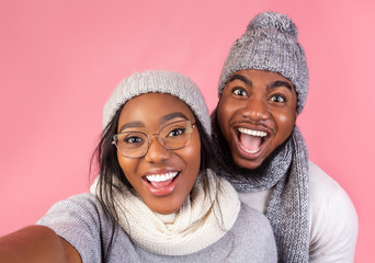 Emotional black winter guy and girl taking selfie together