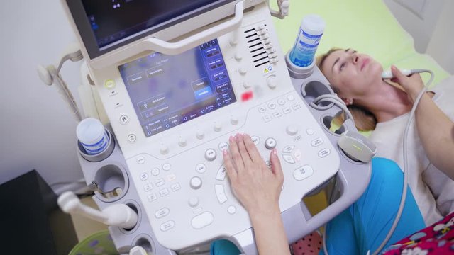 Modern medical equipment in the hospital. Female specialist makes ultrasound scanning diagnostic of thyroid gland to a woman in clinic.