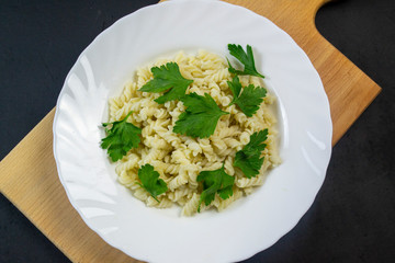 boiled pasta with meatballs on a white plate on a wooden board