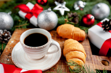 Christmas coffee and croissants with Christmas tree and gifts, toys on a stone background