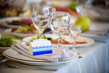 Glasses, forks, knives, napkins and decorative flower on a table served for dinner in cozy restaurant.