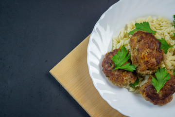 boiled pasta with meatballs on a white plate on a wooden board