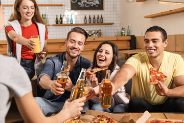 Group of friends having fun party with delicious pizza in cafe