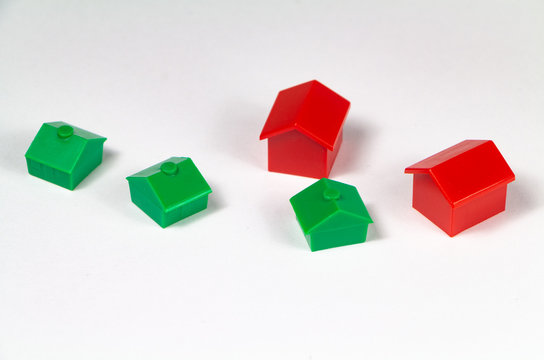 Red and green small plastic houses on white background