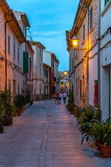 Fototapeta na wymiar Night or blue hour view of a narrow street in the old town of Alcudia, Mallorca, Spain