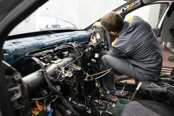 Car mechanic disassembles the interior of the car