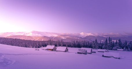 Awesome Winter Scenery. Fantastic winter landscape, footpath the steps that lead to the huts. Magic view in frosty morning with warm pink sunlit. Amazing wintry background. Fantastic Christmas Scene.
